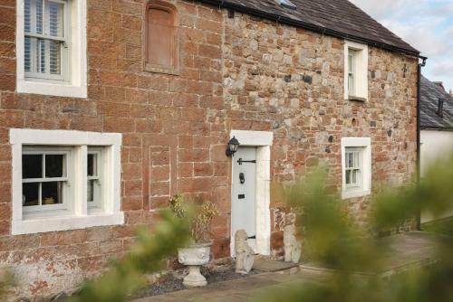 an old brick house with a white door and windows at Glen Bank in Bampton