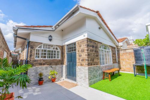 a house with a blue door and green grass at Perfect 2BR Airport Layover Transit Accommodation - High Speed WiFi 30mbps in Nairobi