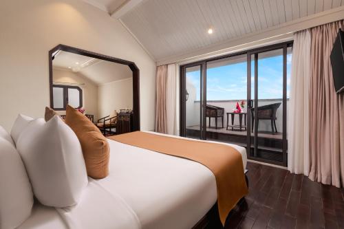 a bedroom with a bed and a large window at Laluna Hoi An Riverside Hotel & Spa in Hoi An