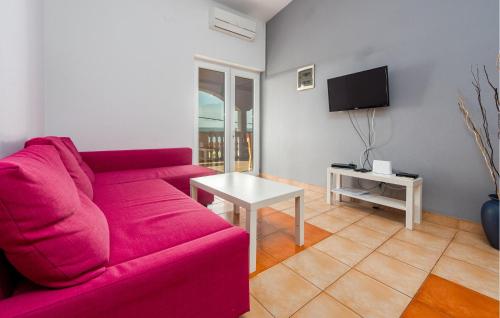 a living room with a red couch and a tv at Cozy Apartment In Maslenica With Wifi in Šarić