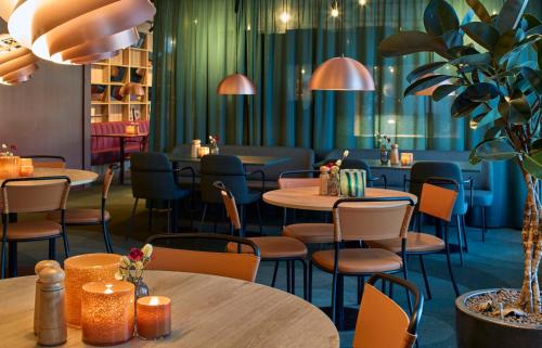 a restaurant with tables and chairs and plants at Scandic Lugnet in Falun