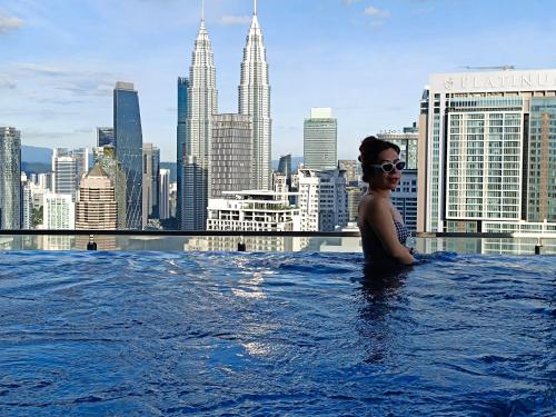 a woman in a infinity pool with a view of a city at The Luxe & Colony Infinitum KLCC by CoupleStay in Kuala Lumpur