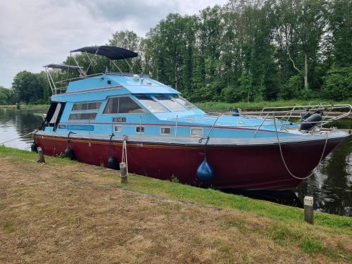 a boat parked on the side of a river at Gezellig overnachten, Luxe boot in Zuidlaren