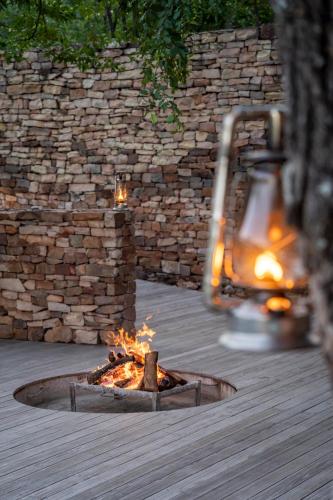 a fire pit on a deck next to a stone wall at The Outpost in Makuleke Contract Park