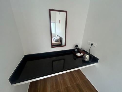 オーロヴィルにあるAuroville Room Guest House Humblepieの黒い洗面台(壁に鏡付)