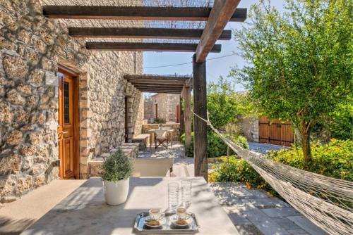 a patio with a hammock and a house at Mare Monte Luxury Suites in Spetses