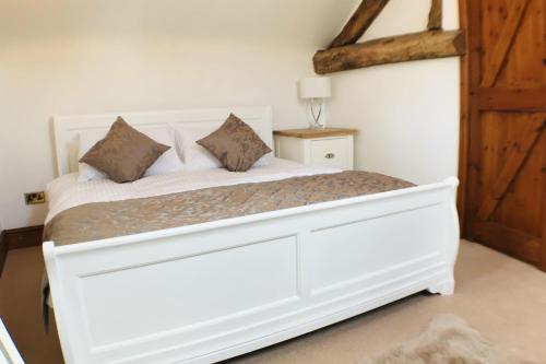 a white bed in a bedroom with a wooden door at Barn Conversion - Sleeps 4 - Pet friendly - Garden in Whiston