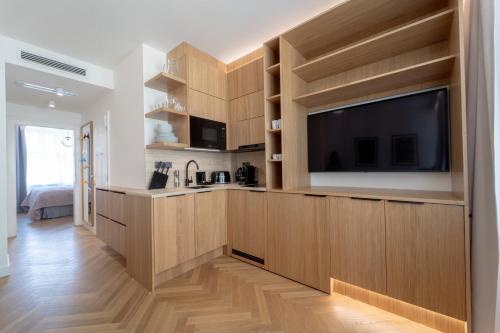 a kitchen with wooden cabinets and a flat screen tv at Six Residences Prague in Prague