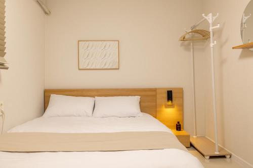 a bedroom with a white bed with a wooden headboard at Harangae in Seoul