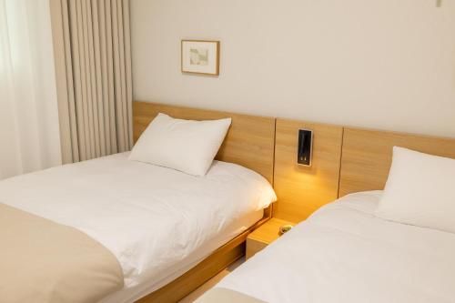 two beds in a hotel room with white sheets at Harangae in Seoul