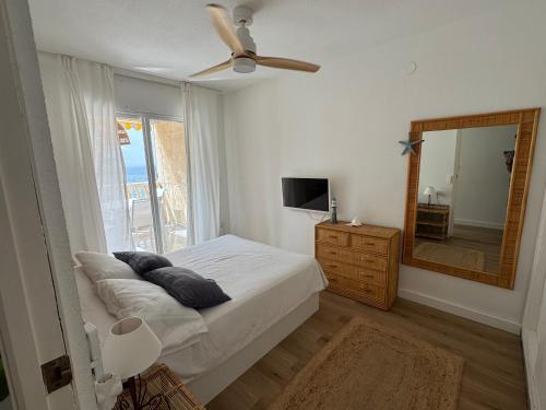 a bedroom with a bed with a ceiling fan and a mirror at Apartamento acogedor con vistas al Mar Menor MINIMO 2 NOCHES in San Javier