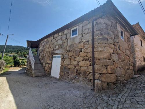 a stone house with a white door and a stone wall at Casa do Apeadeiro in Vila Pouca de Aguiar