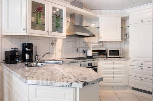 a kitchen with white cabinets and a granite counter top at Ferienwohnung am Schlosssee in Salem
