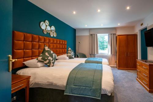 a bedroom with a large bed and blue walls at The Conningbrook Hotel in Ashford