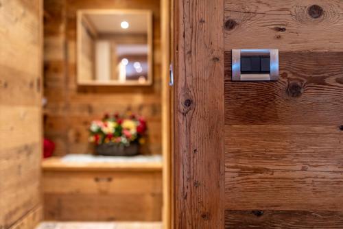 a door to a bathroom with a sink and flowers at Alverà Lodge with Terrace R&R in Cortina dʼAmpezzo
