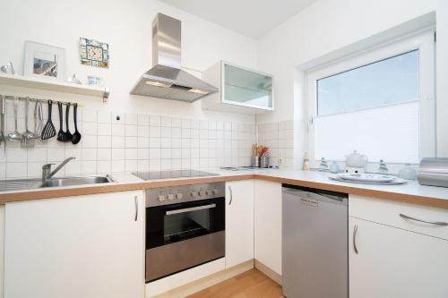 a kitchen with white cabinets and a sink and a window at Baltic Whg 124 in Grömnitzerhagen