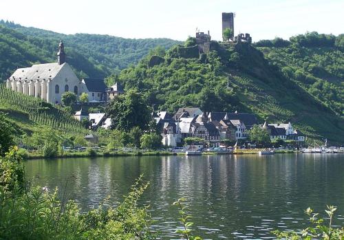 a town on a hill next to a body of water at Pension Mosellablick in Briedern