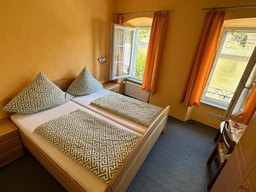 a bedroom with a bed and two windows at Pension Mosellablick in Briedern