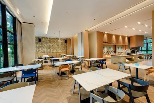 a restaurant with tables and chairs and a kitchen at Holiday Inn Express Haikou West Coast by IHG in Haikou