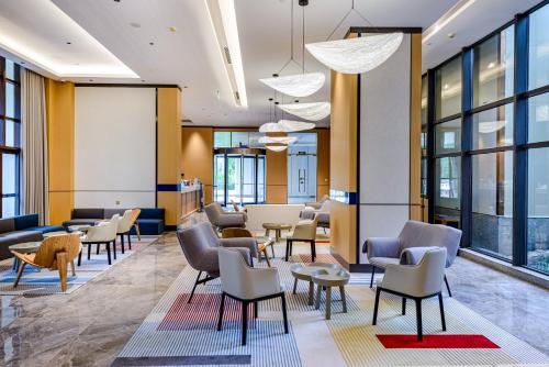 a lobby with chairs and tables and windows at Holiday Inn Express Haikou West Coast by IHG in Haikou