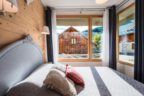 a bedroom with a bed in front of a window at Lune des Alpes - Chalet de charme in Valloire