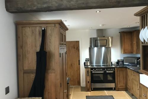 a kitchen with wooden cabinets and a stove top oven at Barn-Sleeps 4-Parking-Near Alton Towers Peak Dist in Waterfall