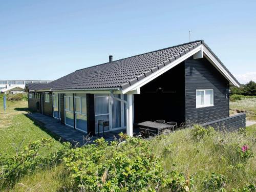 a small black house with a porch and a bench at Luxury Beach House in Blokhus - By Traum Ferienwohnungen in Blokhus