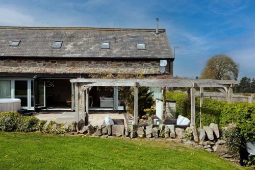 an old house with a stone fence in front of it at Camlad Barn in Chirbury
