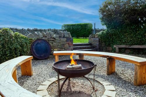 a fire pit in a garden with a bench at Camlad Barn in Chirbury