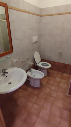 a bathroom with two sinks and a toilet and a mirror at DiMore Apartments - Salento Low Cost in Lizzanello