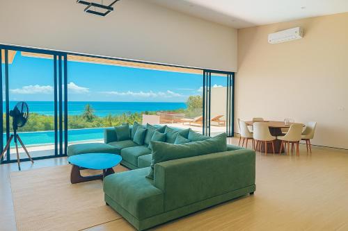 a living room with a green couch and a view of the ocean at Sabanya Sea View Villa in Ban Nua
