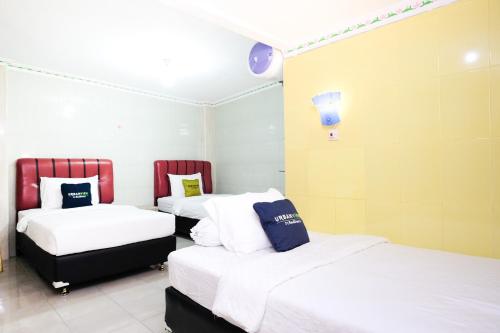 a room with three beds with white and blue pillows at Urbanview Hotel Mawar Sharon near Alun Alun Batu in Batu