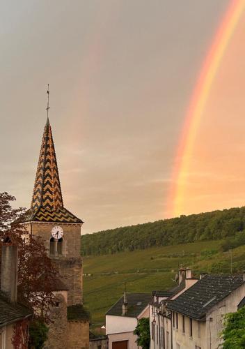 ein Regenbogen am Himmel über einer Stadt mit einem Turm in der Unterkunft A l'ombre des Charlemagnes in Pernand-Vergelesses