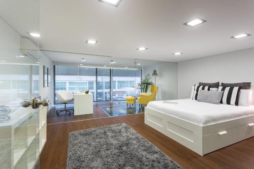 a white bedroom with a large bed and a bathroom at Aveiro Urban Loft in Aveiro