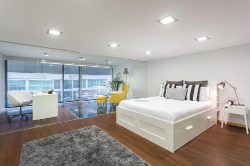 1 dormitorio con 1 cama blanca y sala de estar en Aveiro Urban Loft, en Aveiro