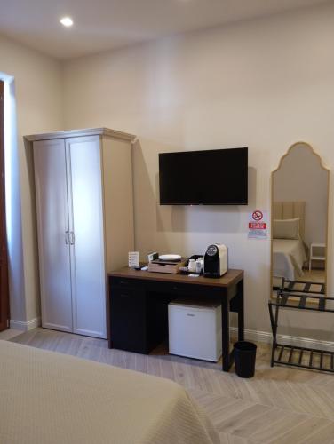 a room with a bed and a desk with a television at Nocera House in Nocera Inferiore