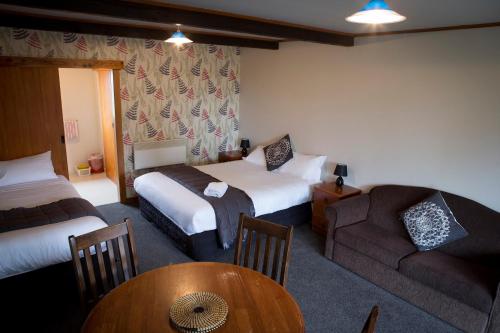um quarto de hotel com duas camas e um sofá e uma mesa em Glentanner Park Centre em Glentanner