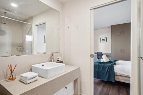 ein Badezimmer mit Waschbecken und Spiegel und einem Bett in der Unterkunft Serenity at Seine Bay 3Brm Apt in Augusta
