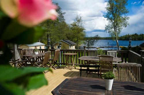 a deck with tables and chairs and a view of a lake at Toftastrand Hotell in Växjö