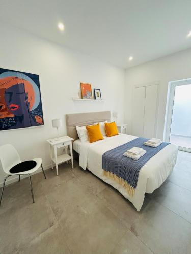 a white bedroom with a large bed and a chair at Casa Eliz Modern Comfort in the center of Faro in Faro