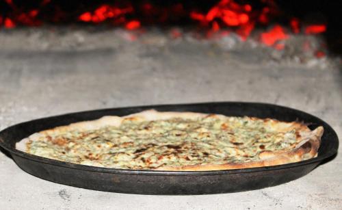 a pizza in a pan in front of a fire at Sigmundenhof Schonach in Schonach