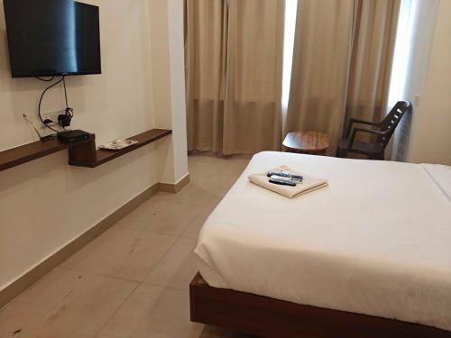 a hotel room with a bed and a television at Temple View Residency in Tiruvallūr
