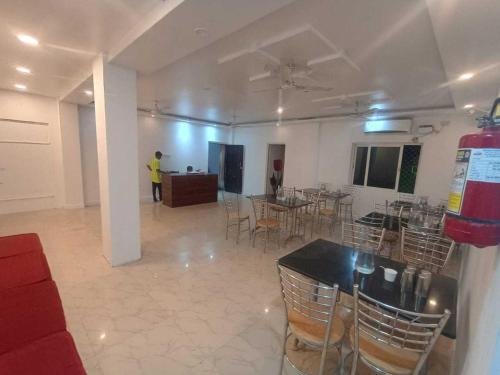 una habitación con mesas y sillas y una persona en el fondo en New Hotel AMR Grand, en Port Blair