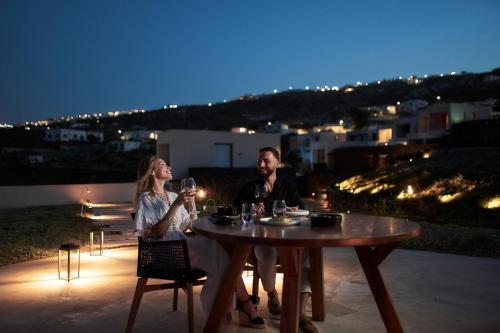 a man and woman sitting at a table with wine glasses at Magma Resort Santorini, In The Unbound Collection By Hyatt in Vourvoulos