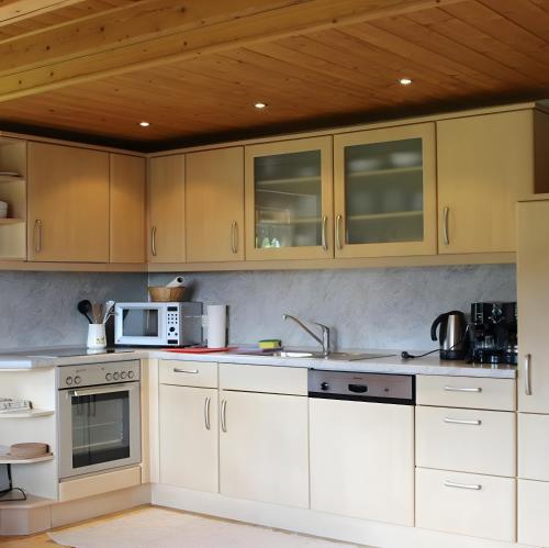 a kitchen with white cabinets and a wooden ceiling at Sigmundenhof Schonach in Schonach