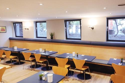 a dining room with tables and chairs and windows at Garner Hotel Cologne East by IHG in Cologne