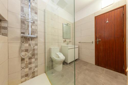 um banheiro com vaso sanitário e uma porta de vidro em Praia da Rocha Beach Step em Portimão