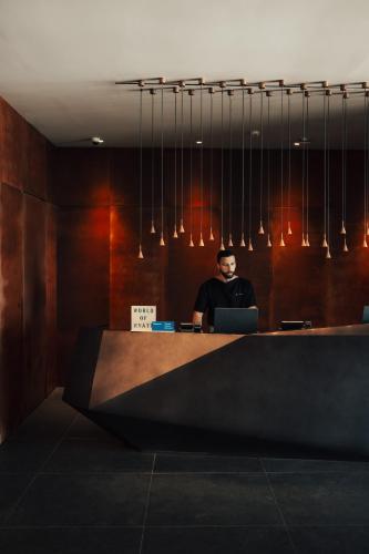 a man sitting at a desk with a laptop at Magma Resort Santorini, In The Unbound Collection By Hyatt in Vourvoulos