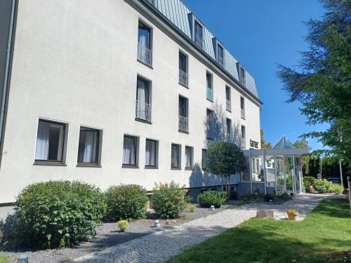 a large white building with bushes in front of it at Garner Hotel Cologne East by IHG in Cologne