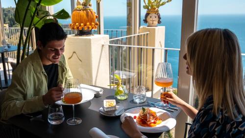 a man and a woman sitting at a table eating food at Hotel Metropole Taormina in Taormina